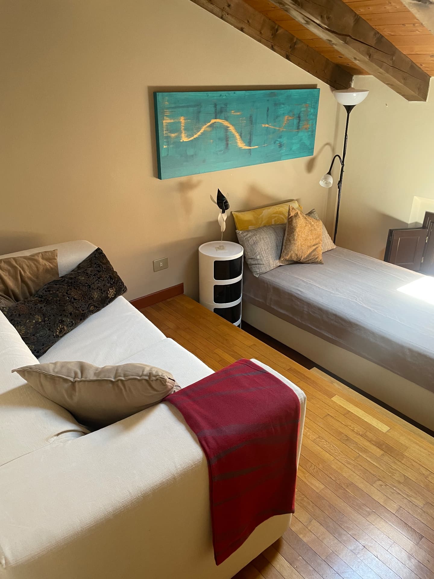 Second bedroom seen along the parquet floor, with both beds and the painting