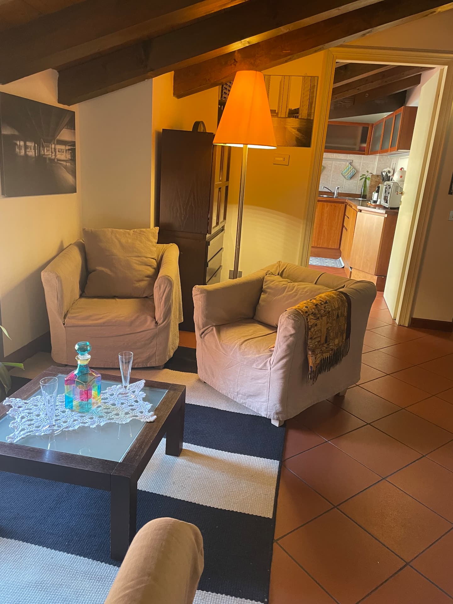 Two linen armchairs and a low table in the living room, with the kitchen doorway beyond