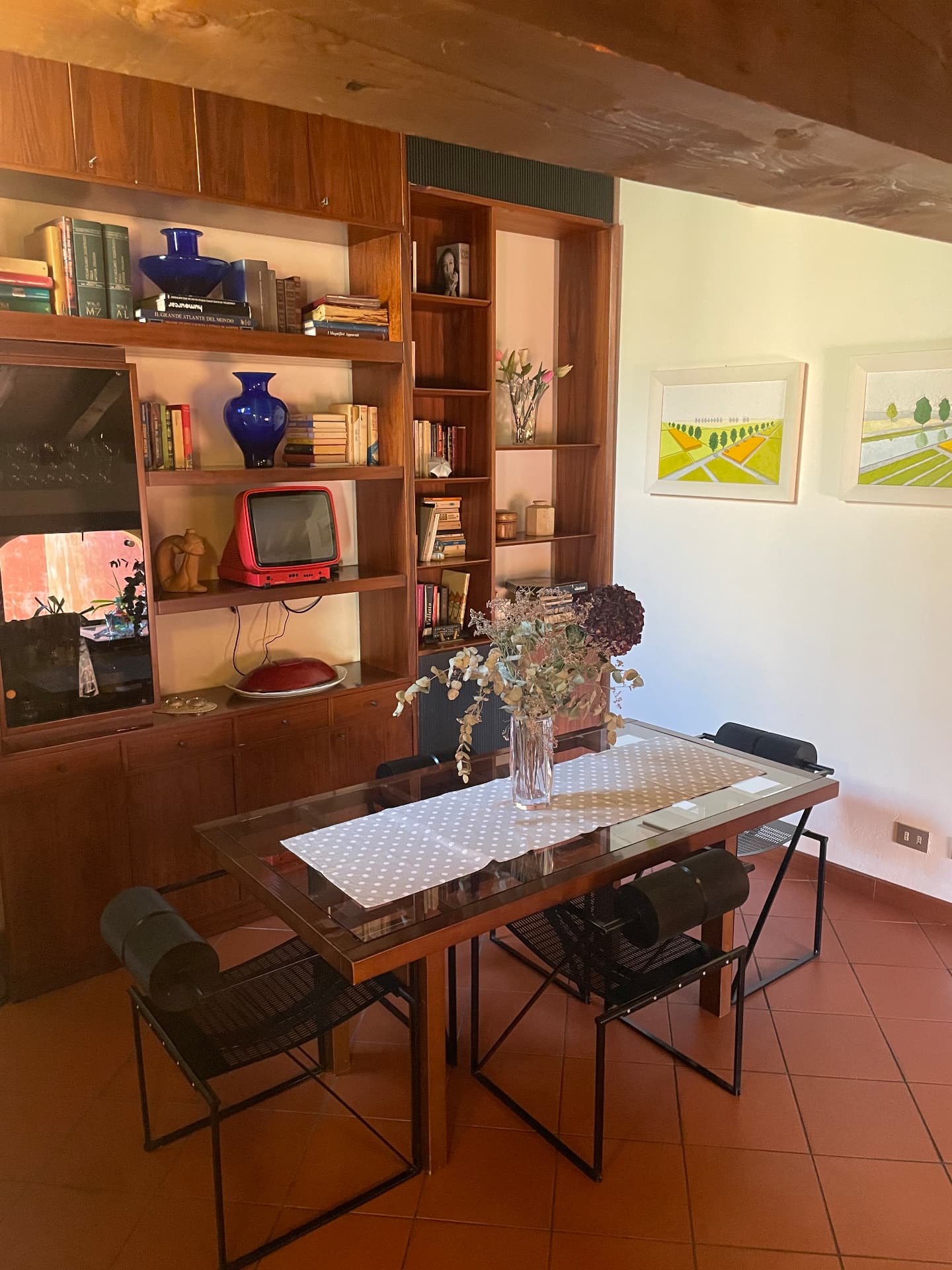Dining room with wooden shelving, framed landscape prints and a table set for four